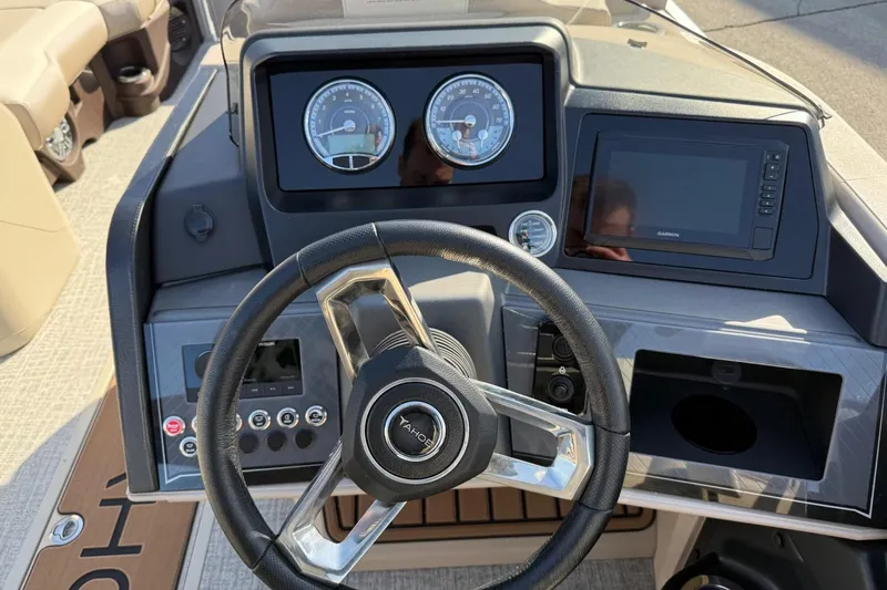Slide: The Image of 2025 Tahoe 2385 boat dashboard with steering wheel, gauges, and navigation display. - 16
