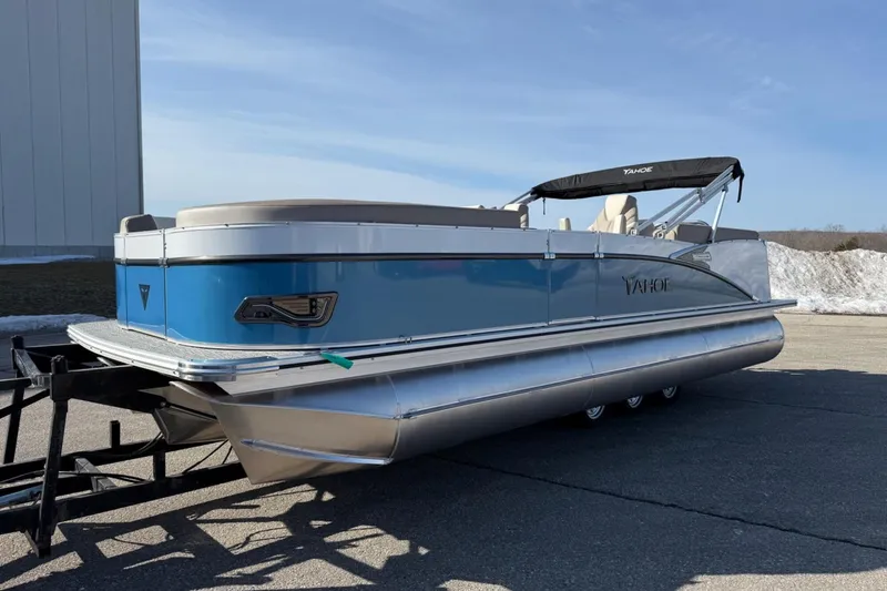 Slide: The Image of 2025 Tahoe 2385 pontoon boat with blue exterior on a trailer, parked outdoors. - 2