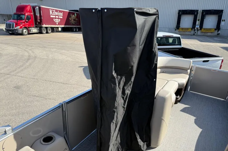 Slide: The Image of 2025 Tahoe 2385 boat interior with seating and privacy curtain in a parking lot. - 25