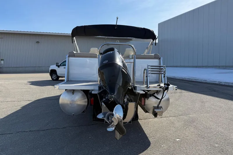 Slide: The Image of 2025 Tahoe 2385 boat with outboard motor, parked on pavement near industrial building. - 4