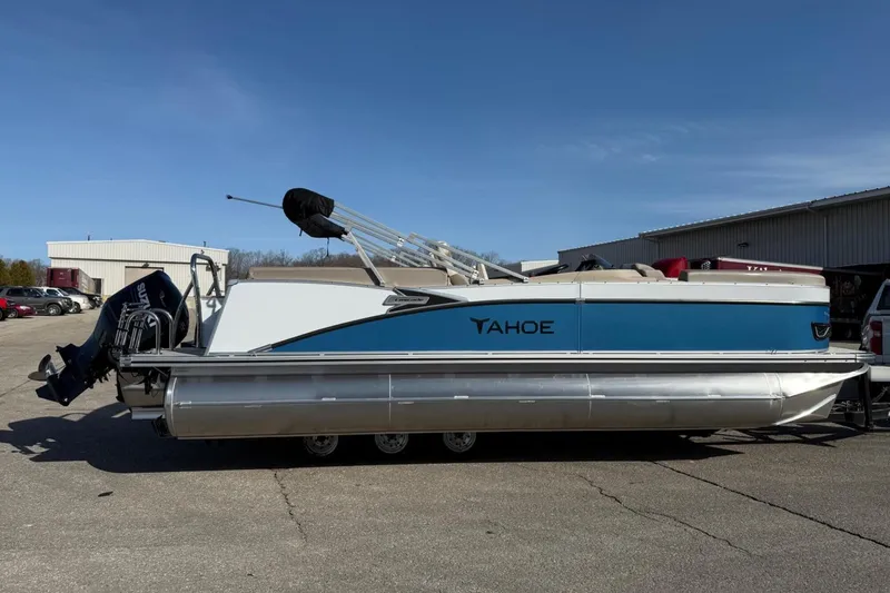 Slide: The Image of 2025 Tahoe 2385 pontoon boat with blue and white design, parked outdoors. - 8