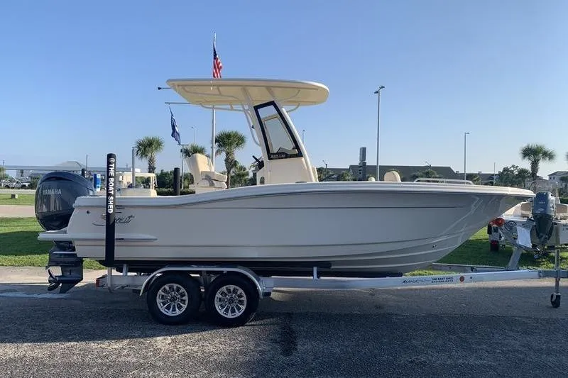 Slide: The Image of 2026 Scout 215 XSF boat on trailer, parked outdoors under clear sky. - 5