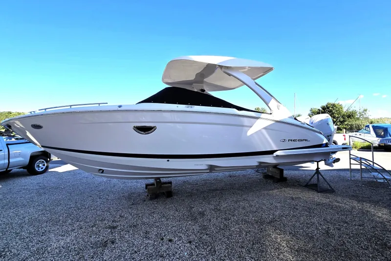 The Image of 2026 Regal LX9 boat on display, elevated on stands, under clear blue sky. - 0