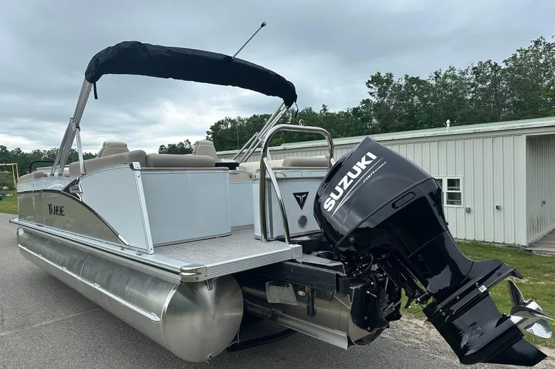 Slide: The Image of 2025 Tahoe 2385 pontoon boat with Suzuki outboard motor, parked near a building. - 4