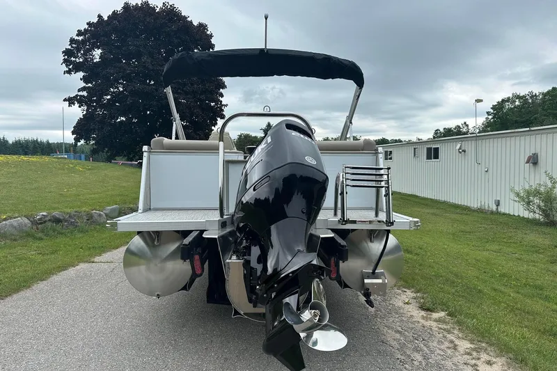 Slide: The Image of 2025 Tahoe 2385 pontoon boat with powerful outboard motor on a grassy area. - 5