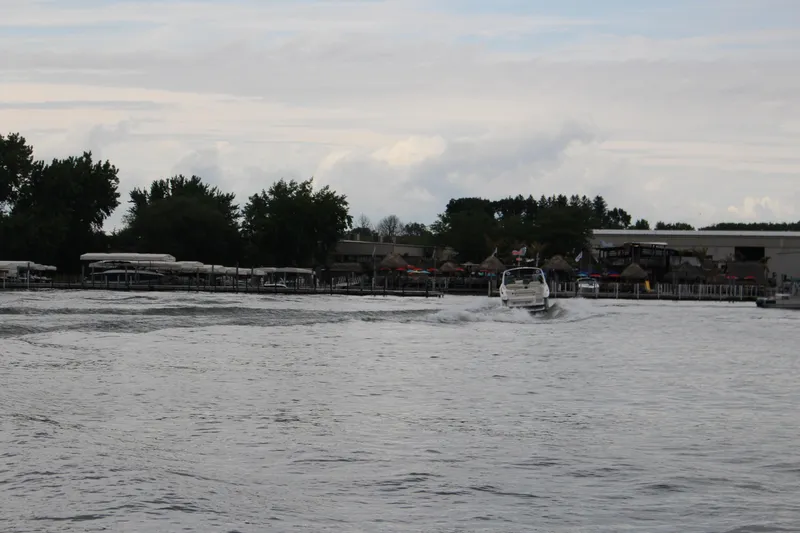 Slide: The Image of 2021 Cobalt R35 Surf boat cruising on a lake near a marina with trees and buildings. - 25