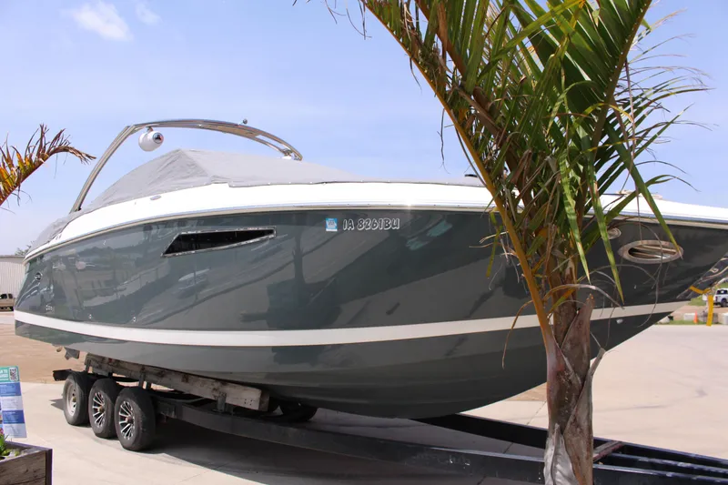 Slide: The Image of 2021 Cobalt R35 Surf boat on trailer, partially covered, with palm trees nearby. - 4