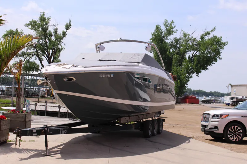 Slide: The Image of 2021 Cobalt R35 Surf boat on trailer, parked near a marina with trees in the background. - 5