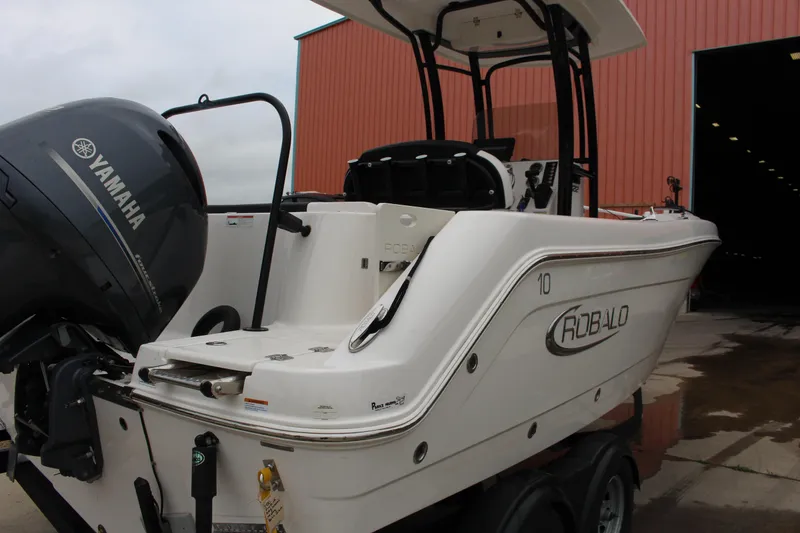 Slide: The Image of 2021 Robalo 222EX boat with Yamaha engine near a red building. - 2