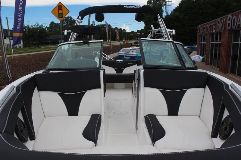 Slide: The Image of 2018 MasterCraft XT22 boat interior with black and white seating, parked near a dealership. - 8