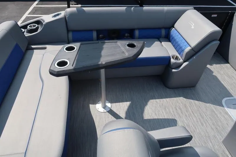 Slide: The Image of 2022 Bennington 23 LSB boat interior with gray and blue seating, table, and cup holders. - 19