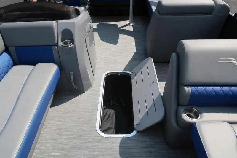 Slide: The Image of 2022 Bennington 23 LSB boat interior with open storage compartment and blue-gray seating. - 29