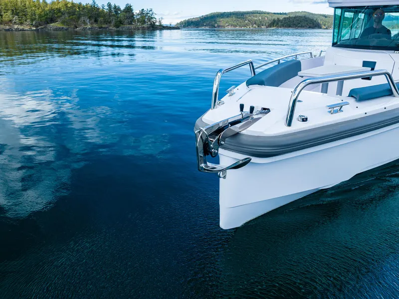 Slide: The Image of Axopar 28 boat, 2022 model, cruising on clear blue water near a forested shoreline. - 10