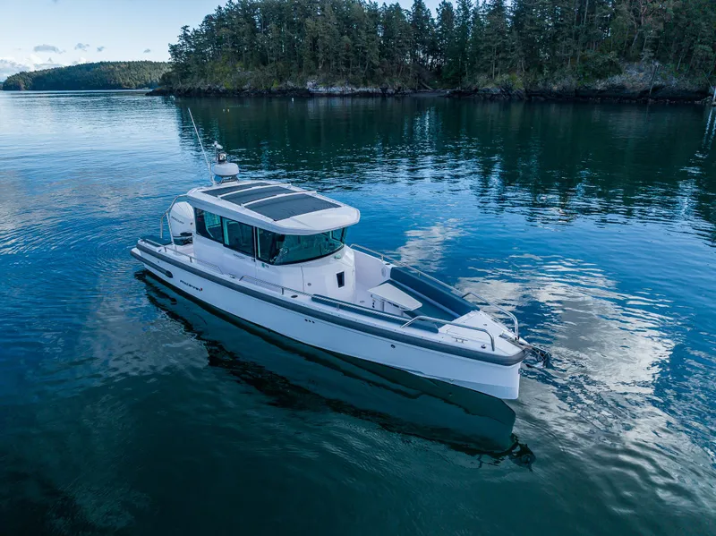 Slide: The Image of Axopar 28 boat, 2022 model, cruising on calm waters near a forested shoreline. - 21