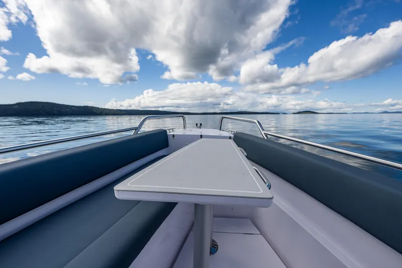 Slide: The Image of Axopar 28 boat interior with table, 2022 model, on calm water under cloudy sky. - 22
