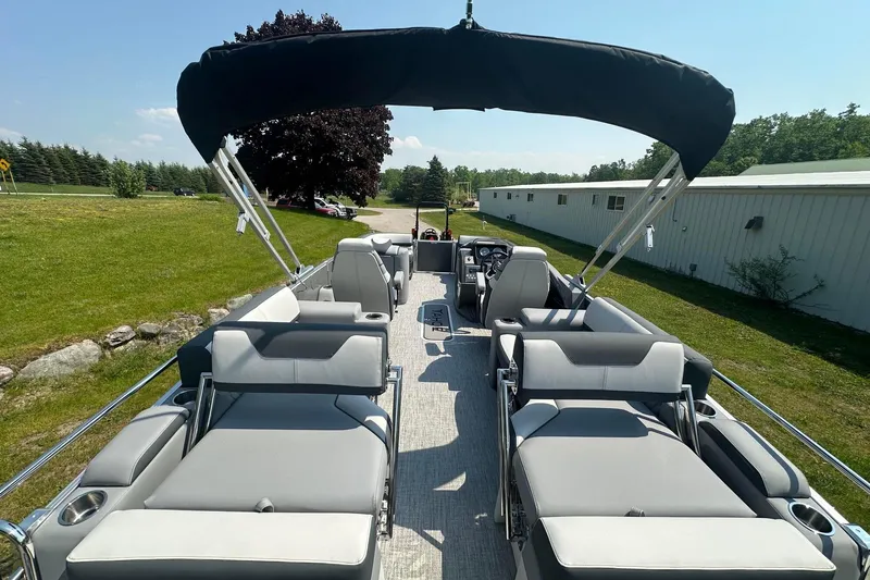 Slide: The Image of 2025 Tahoe 2385 pontoon boat with spacious seating and canopy, parked on grassy area. - 10