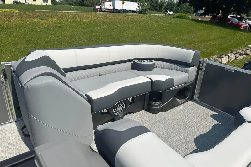Slide: The Image of 2025 Tahoe 2385 boat interior with gray seating and cup holders on a sunny day. - 16