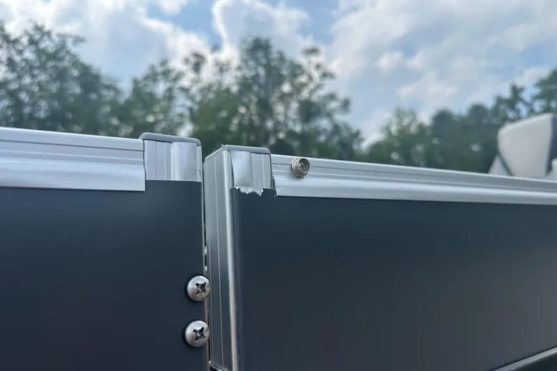 Slide: The Image of Close-up of 2025 Tahoe 2385 boat railing with screws and slight damage, under cloudy sky. - 28