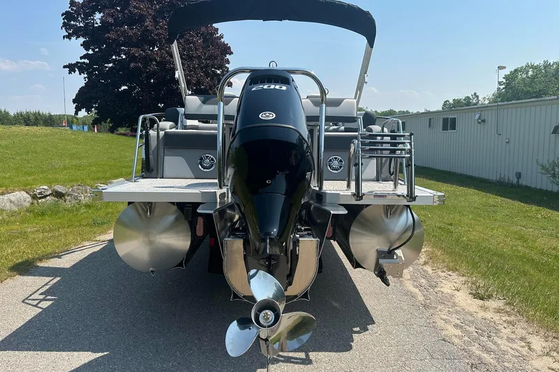 Slide: The Image of 2025 Tahoe 2385 pontoon boat with powerful outboard motor, parked on a sunny day. - 7
