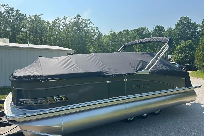 Slide: The Image of 2025 Tahoe 2385 pontoon boat with cover, parked outdoors on a sunny day. - 9