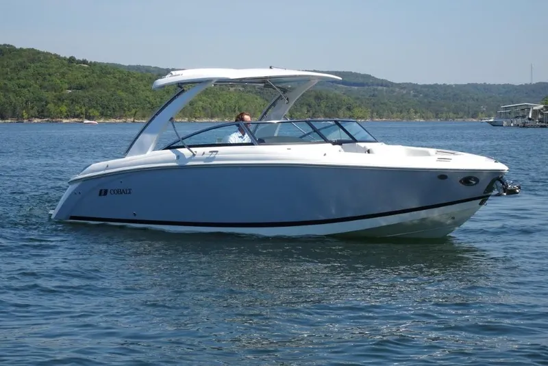 Slide: The Image of 2025 Cobalt R30 boat cruising on a scenic lake with lush green hills. - 1