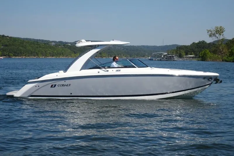 Slide: The Image of 2025 Cobalt R30 boat cruising on a scenic lake with lush green hills. - 2