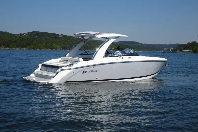 Slide: The Image of 2025 Cobalt R30 boat cruising on a scenic lake with lush green hills. - 3