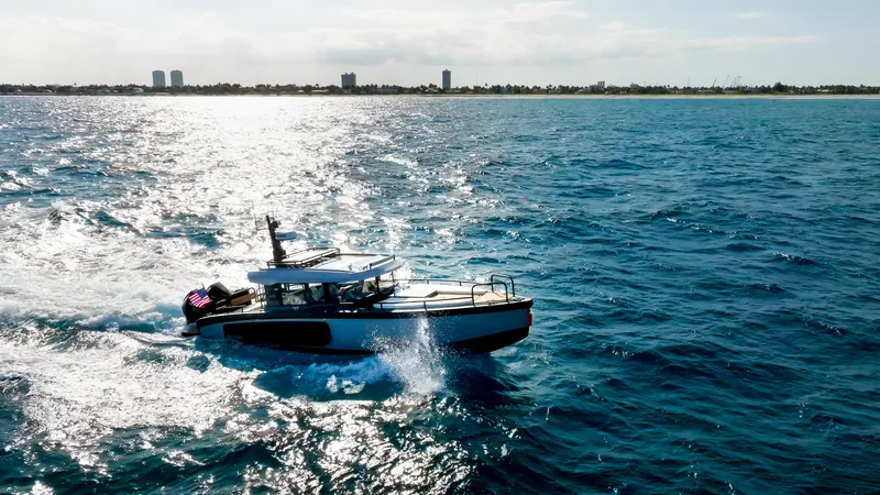 Slide: The Image of 2023 Arksen 30 boat cruising on open ocean with city skyline in background. - 16