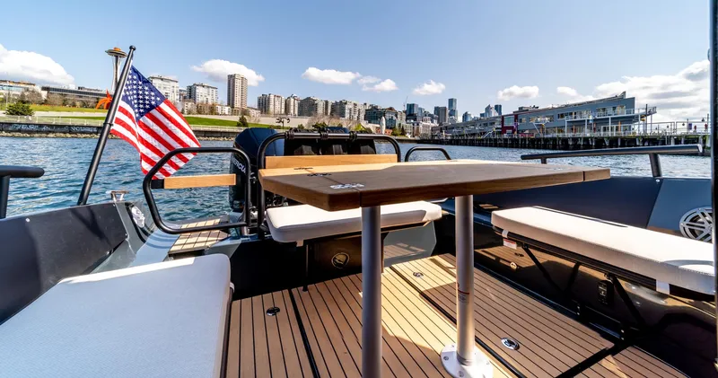 Slide: The Image of 2023 Arksen 30 boat with American flag, docked in urban waterfront setting. - 47