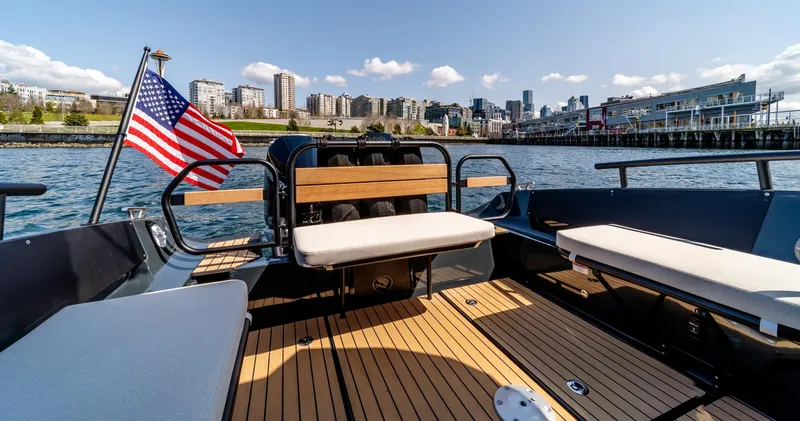 Slide: The Image of 2023 Arksen 30 boat with American flag, city skyline in background, sunny day. - 48