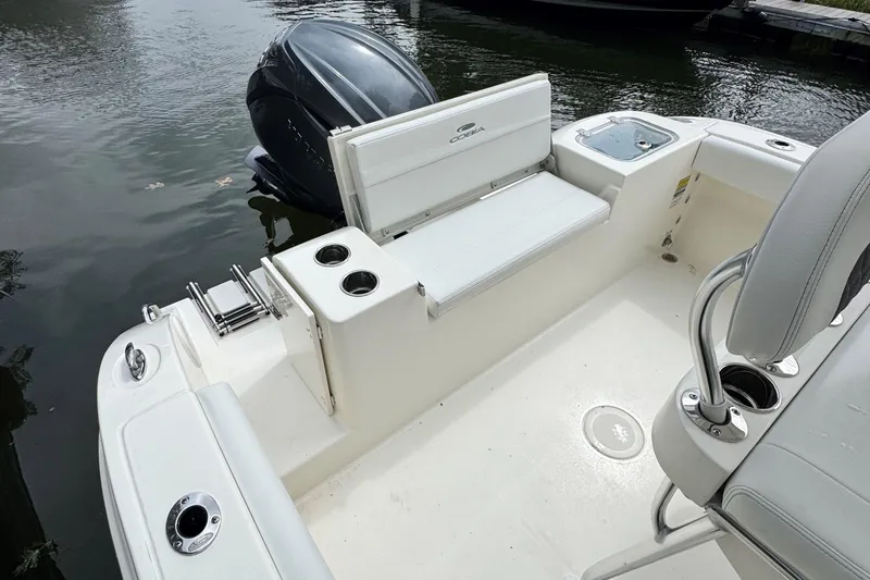 Slide: The Image of 2026 Cobia 220 Center Console boat interior with seating and motor, docked on water. - 6