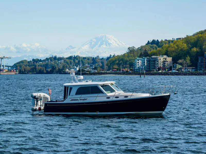 Slide: The Image of 2013 Back Cove 37 yacht on scenic water with mountain and city backdrop. - 17