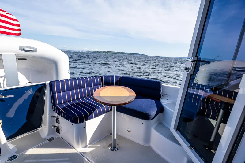 Slide: The Image of 2013 Back Cove 37 yacht with striped seating and table, overlooking the ocean. - 35