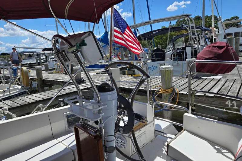 Slide: The Image of Sailboat docked at marina, featuring a 1992 Hunter 35.5 model with American flag. - 35