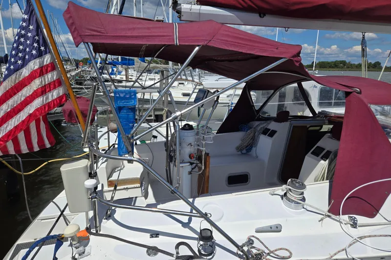 Slide: The Image of Sailboat cockpit with maroon canopy, American flag, and marina background, Hunter 35.5, 1992 model. - 36