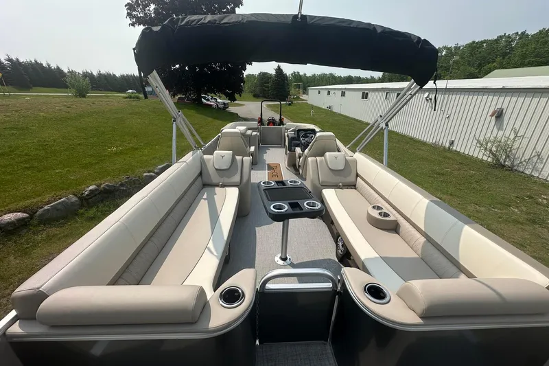 Slide: The Image of 2025 Tahoe 2585 pontoon boat with spacious seating and canopy, parked on grass. - 21
