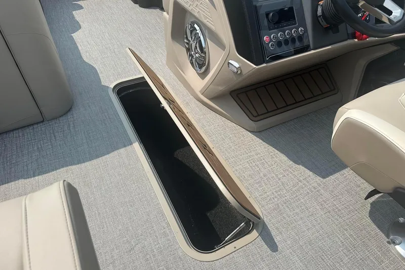 Slide: The Image of 2025 Tahoe 2585 boat interior with open storage compartment and control panel. - 22