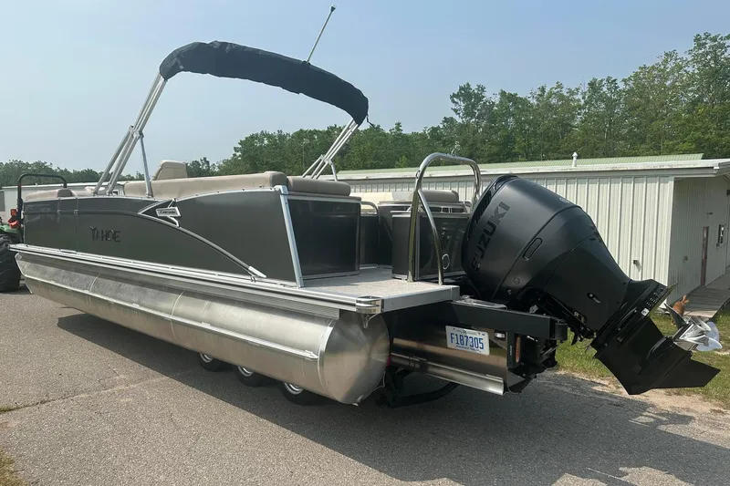 Slide: The Image of 2025 Tahoe 2585 pontoon boat with Suzuki outboard motor, parked on a paved surface. - 3