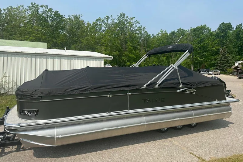 Slide: The Image of 2025 Tahoe 2585 pontoon boat with black cover, parked outdoors. - 8