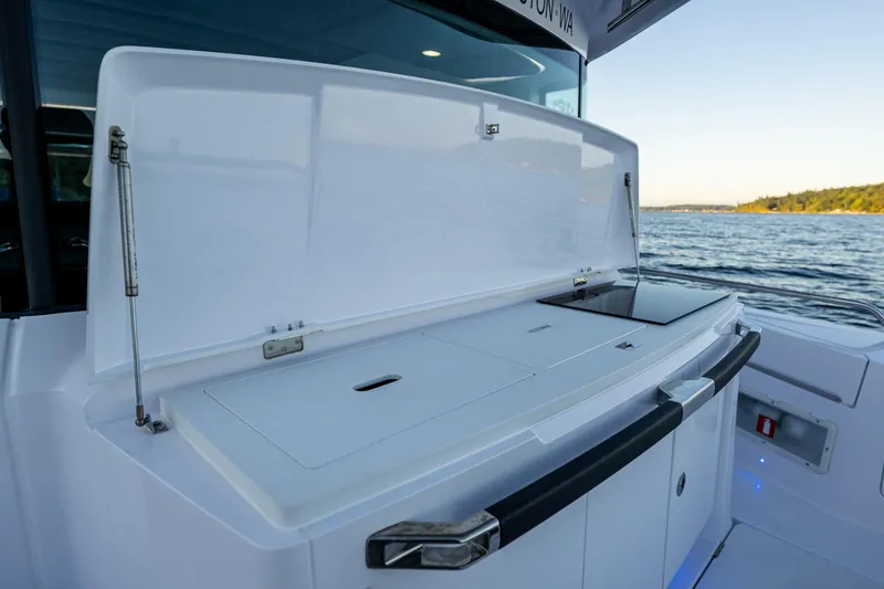 Slide: The Image of Axopar 37 XC 2022 boat with open storage compartment by the water. - 26