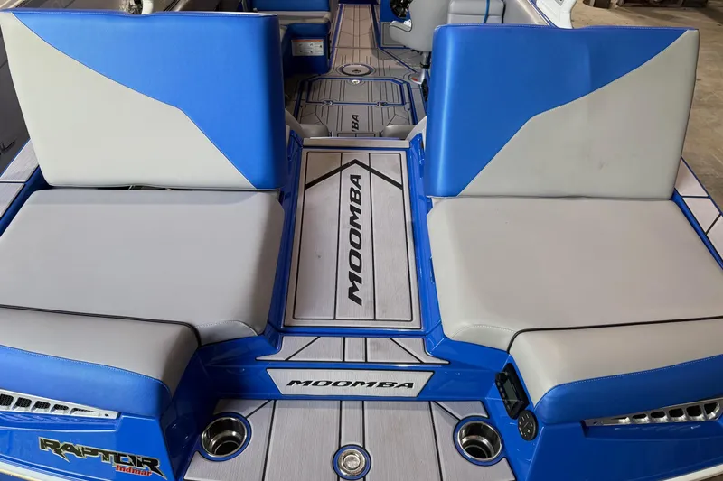 Slide: The Image of 2023 Moomba Mojo boat interior with blue and gray seating, featuring Raptor Indmar branding. - 3
