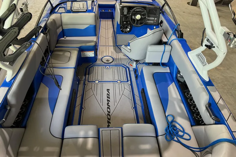Slide: The Image of 2023 Moomba Mojo boat interior with blue and gray seating, steering wheel, and deck design. - 4