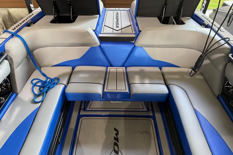 Slide: The Image of 2023 Moomba Mojo boat interior with blue and gray seating, featuring storage compartments. - 6
