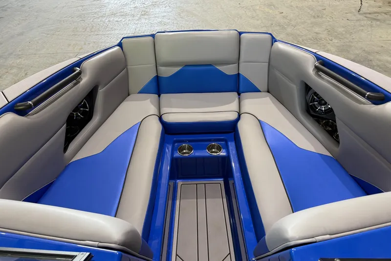 Slide: The Image of 2023 Moomba Mojo boat interior with blue and gray seating, cup holders, and speakers. - 7