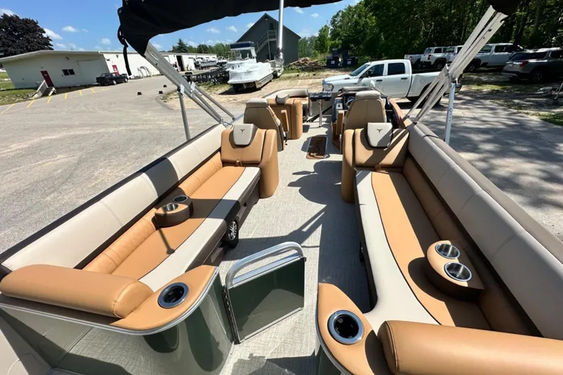 Slide: The Image of 2025 Tahoe 2585 pontoon boat with luxurious seating and cup holders, parked outdoors. - 11
