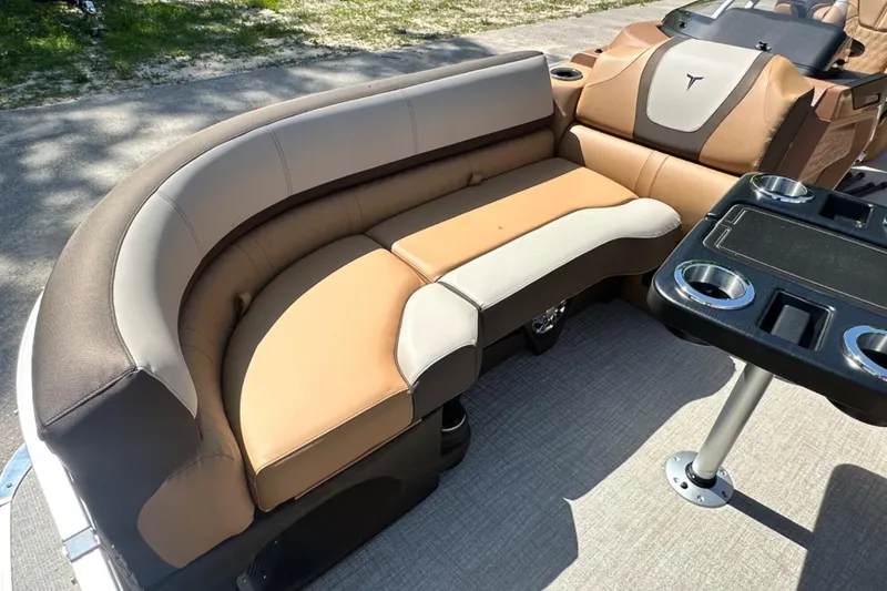 Slide: The Image of 2025 Tahoe 2585 boat interior with tan and brown seating, cup holders, and table. - 19