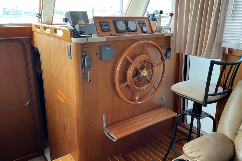 Slide: The Image of 1999 Mainship 350 Trawler helm with wooden wheel, navigation instruments, and captain's chair. - 13