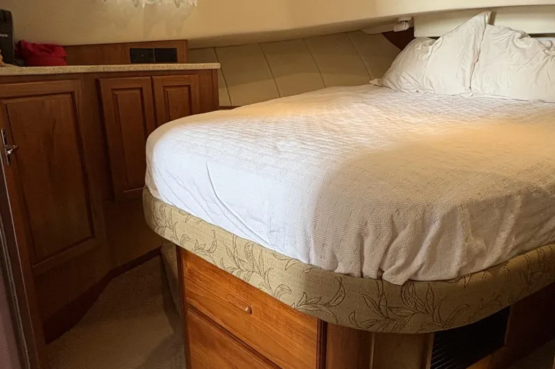 Slide: The Image of Cozy bedroom interior of 1999 Mainship 350 Trawler with wooden cabinetry and white bedding. - 20