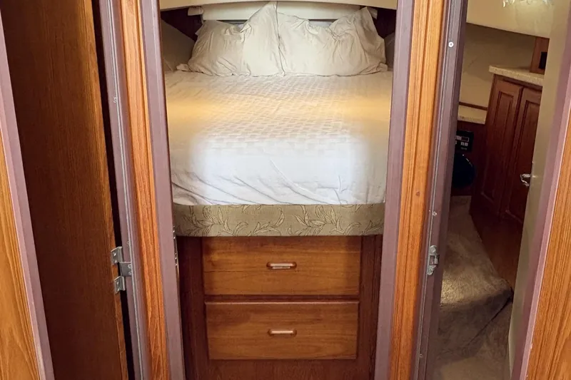 Slide: The Image of 1999 Mainship 350 Trawler cabin with cozy bed and wooden storage drawers. - 21