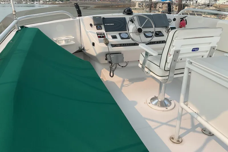 Slide: The Image of 1999 Mainship 350 Trawler helm with steering wheel, controls, and green cover. - 8